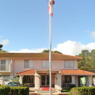 A residential building with a flagpole in front, set against a clear blue sky.