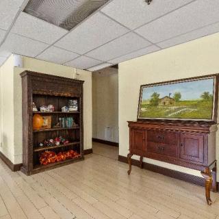 A room interior with wooden furniture, featuring a cabinet filled with decorative items and a painting above a sideboard.