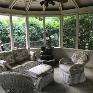 A cozy sunroom with wicker furniture overlooking a lush garden.