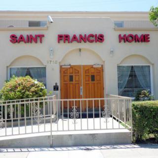 Entrance of the Saint Francis Home with a ramp and surrounding bushes.