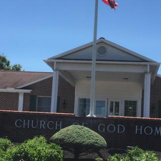 The Church of God Home, featuring a flag and well-maintained landscaping.