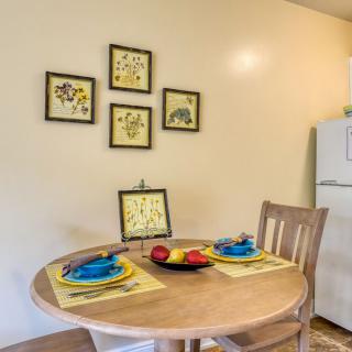 A cozy dining area with a wooden table set for two, featuring colorful plates and utensils.