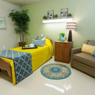 A cozy bedroom with a brightly colored bedspread, matching decor, and comfortable seating.