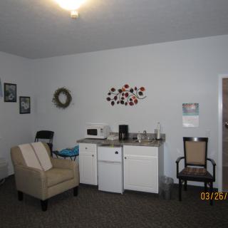 A cozy living room with a kitchenette and simple decor.