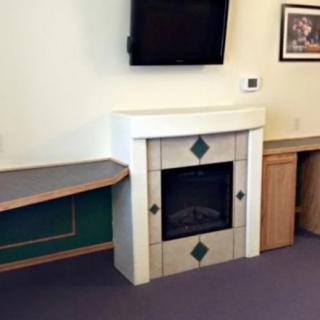 A room with a modern fireplace, television mounted above, and a desk area.