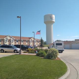 A serene view of a residential area featuring a water tower and an American flag under a clear blue sky.
