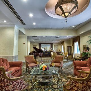 A luxurious hotel lobby featuring elegant seating, a grand piano, and a chandelier.