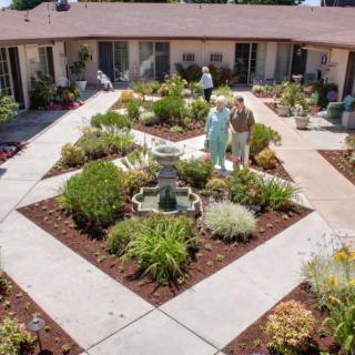 A courtyard garden with a central fountain, surrounded by pathways and lush plants.