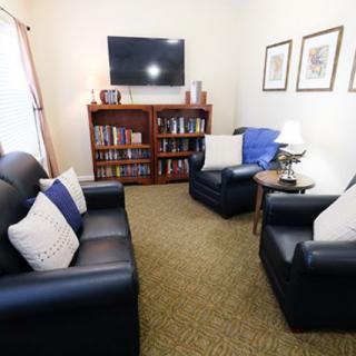 A cozy living room with comfortable seating, bookshelves, and a television.