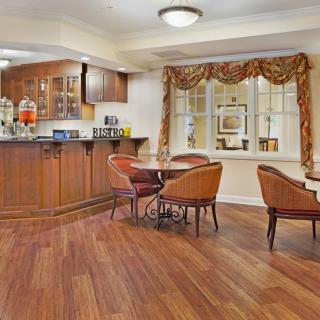 A cozy dining area with a kitchen featuring wooden cabinets and flooring.