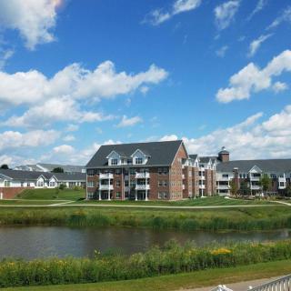 Scenic view of residential buildings by a lake under a partly cloudy sky.