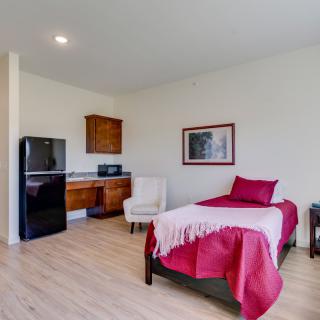 A minimalist bedroom with a single bed and a small kitchenette.