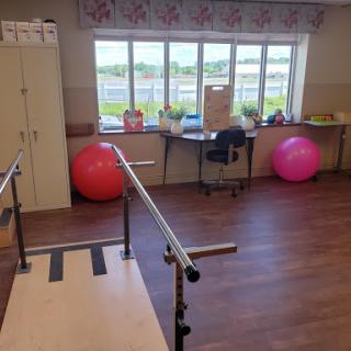 A well-equipped therapy room featuring balance bars and exercise balls, designed for rehabilitation and fitness activities.