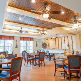 A cozy dining area with wooden accents, featuring tables and chairs under a warm, well-lit ceiling.