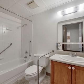 A modern bathroom featuring a bathtub, toilet, and sink with a mirror above.