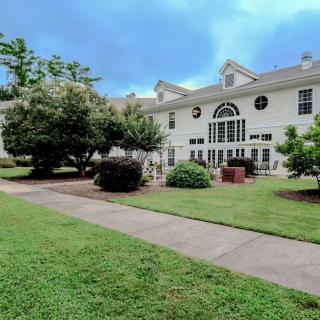 A large residential house with a well-maintained lawn and surrounding trees.