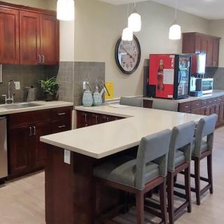 A modern kitchen interior featuring a central counter with bar stools and sleek appliances.