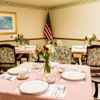 A neatly arranged dining room with floral patterns and an American flag in the background.