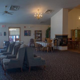 A spacious living room with chairs, tables, and a fireplace.