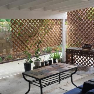 A cozy outdoor patio with a table, potted plants, and a lattice fence.