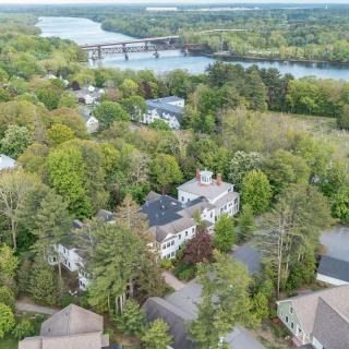 Aerial view of a lush, green neighborhood with houses surrounded by trees and a river in the background.