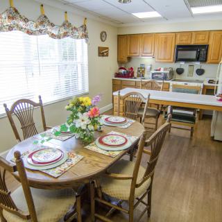 A cozy kitchen and dining area with a table set for four, featuring wooden furniture and modern appliances.