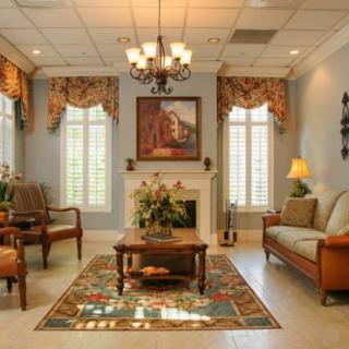 A traditionally decorated living room with a chandelier, fireplace, and classic furniture.