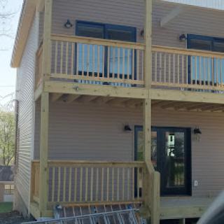 A modern two-story building featuring wooden balconies and a welcoming entrance.