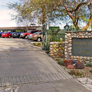 Entrance to a parking lot with a stone sign and surrounding trees.
