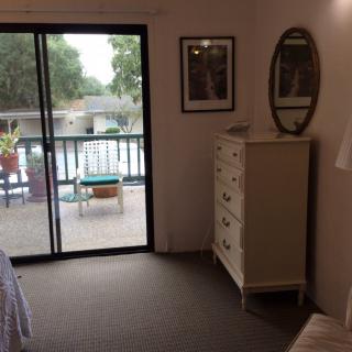 A cozy bedroom with a dresser and mirror, featuring a sliding door leading to a balcony.