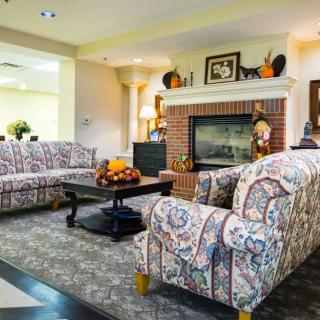 A cozy living room with patterned sofas and a warm fireplace.