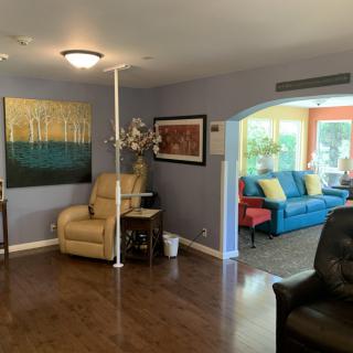 A cozy living room featuring a beige armchair, colorful sofa, and modern artwork on the walls.