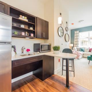 A modern kitchen with sleek cabinetry, a stainless steel fridge, and a cozy seating area.