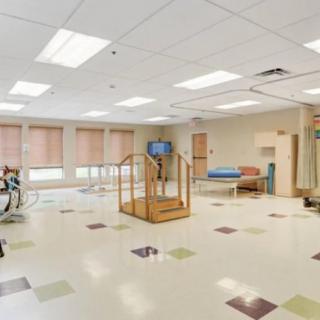 A spacious rehabilitation therapy room equipped with exercise equipment and a wooden staircase.