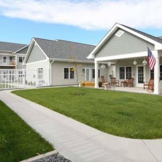 A residential building with a well-maintained lawn and an American flag on the porch.