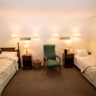 A cozy bedroom featuring twin beds with warm lighting and classic furnishings.