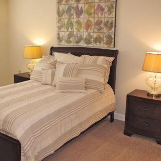 A cozy bedroom with a neatly made bed, nightstands, and warm lighting.