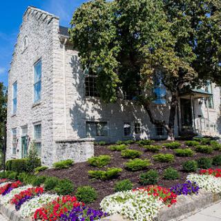 A charming stone building surrounded by a colorful flower garden and lush greenery.