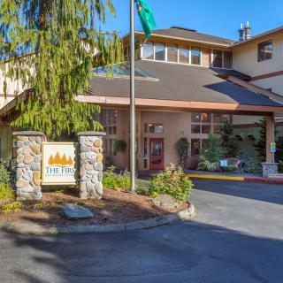 The exterior view of a hotel entrance with a visible sign and surrounding trees.