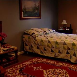 A cozy bedroom with a quilted bed, side table, and a decorative rug.