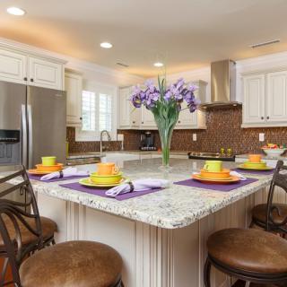 A modern kitchen with a central island featuring colorful table settings and flowers.