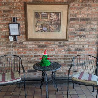 A cozy corner with two chairs, a small table adorned with festive decor, and a framed painting on a brick wall.