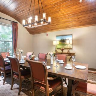A cozy dining room with a large table, surrounded by cushioned chairs and topped with elegant tableware.