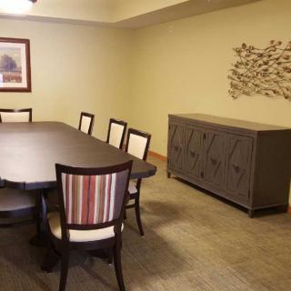 A dining room setup with a large table, chairs, artwork on the wall, and a sideboard.