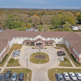 Aerial view of a large building with a circular driveway and surrounding parking area.