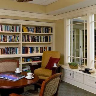 A cozy reading room with bookshelves, an armchair, and a table set for coffee.