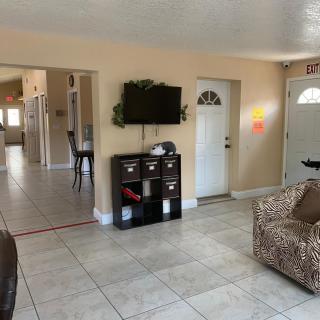 A cozy living room with a tiled floor, featuring a sofa, TV, and door entryway.
