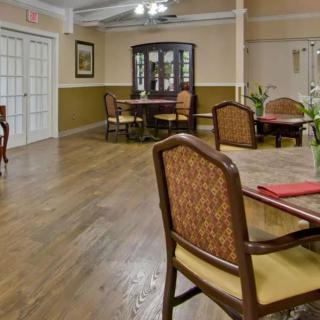 A well-furnished dining room with elegant chairs and tables on a hardwood floor.