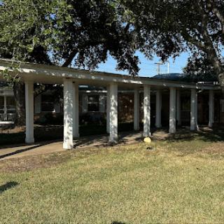 A modern architectural structure featuring columns and greenery.