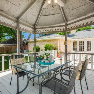 A cozy gazebo with a glass dining table and chairs, nestled in a backyard setting.